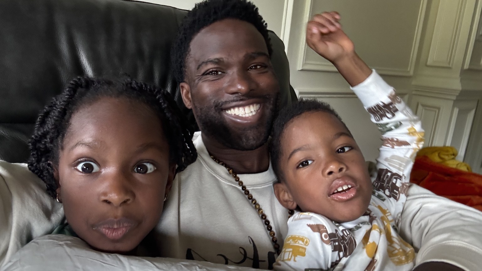 Phil BeLight smiling with his children on the couch