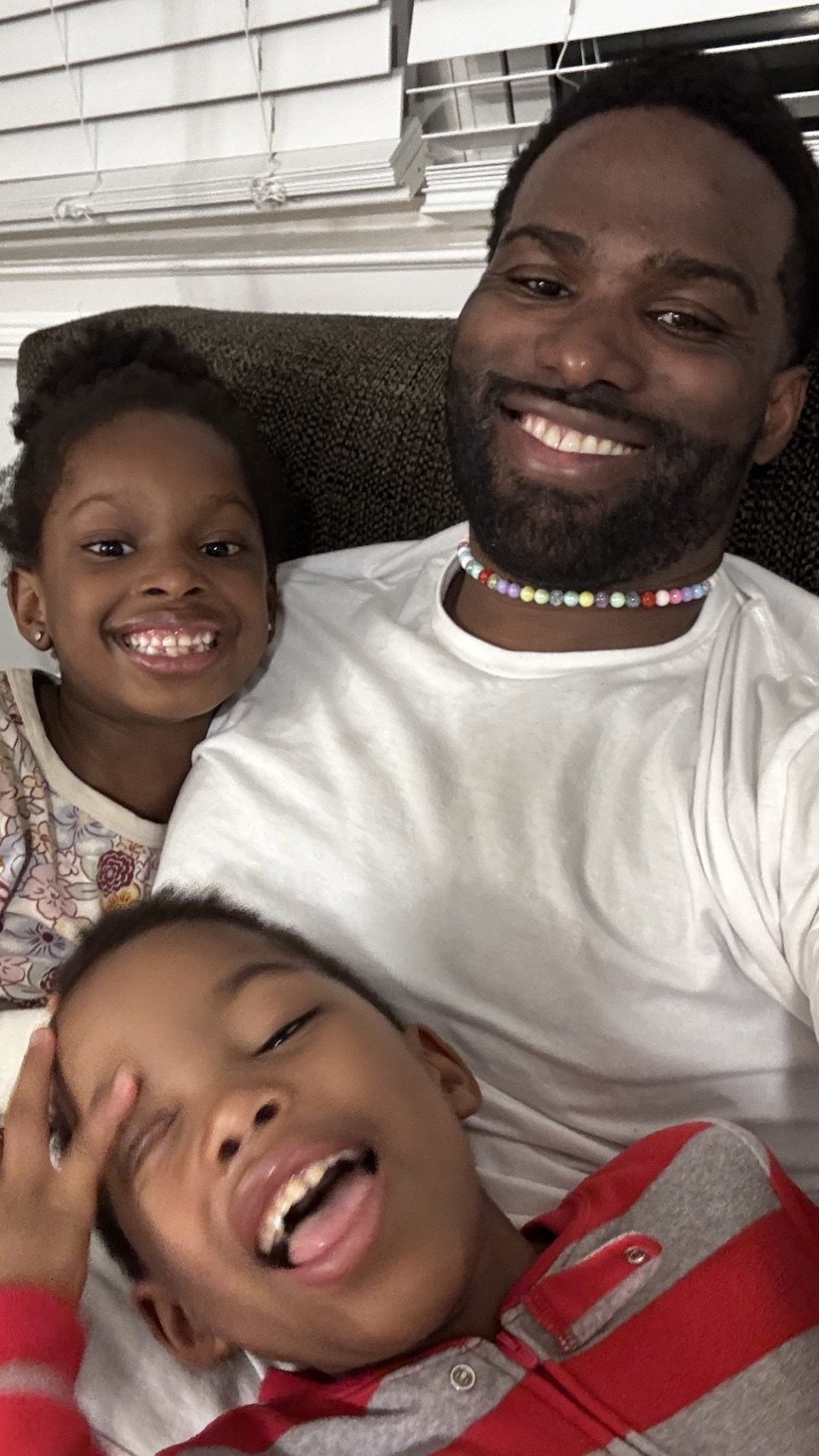Phil BeLight smiling with his children at home