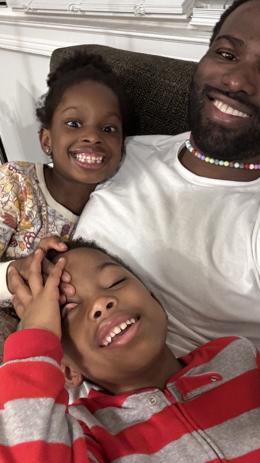 Phil BeLight smiling with his children at home