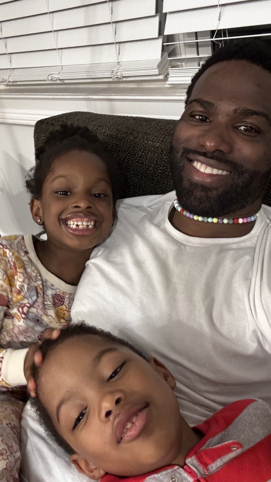 Phil BeLight smiling with his children at home